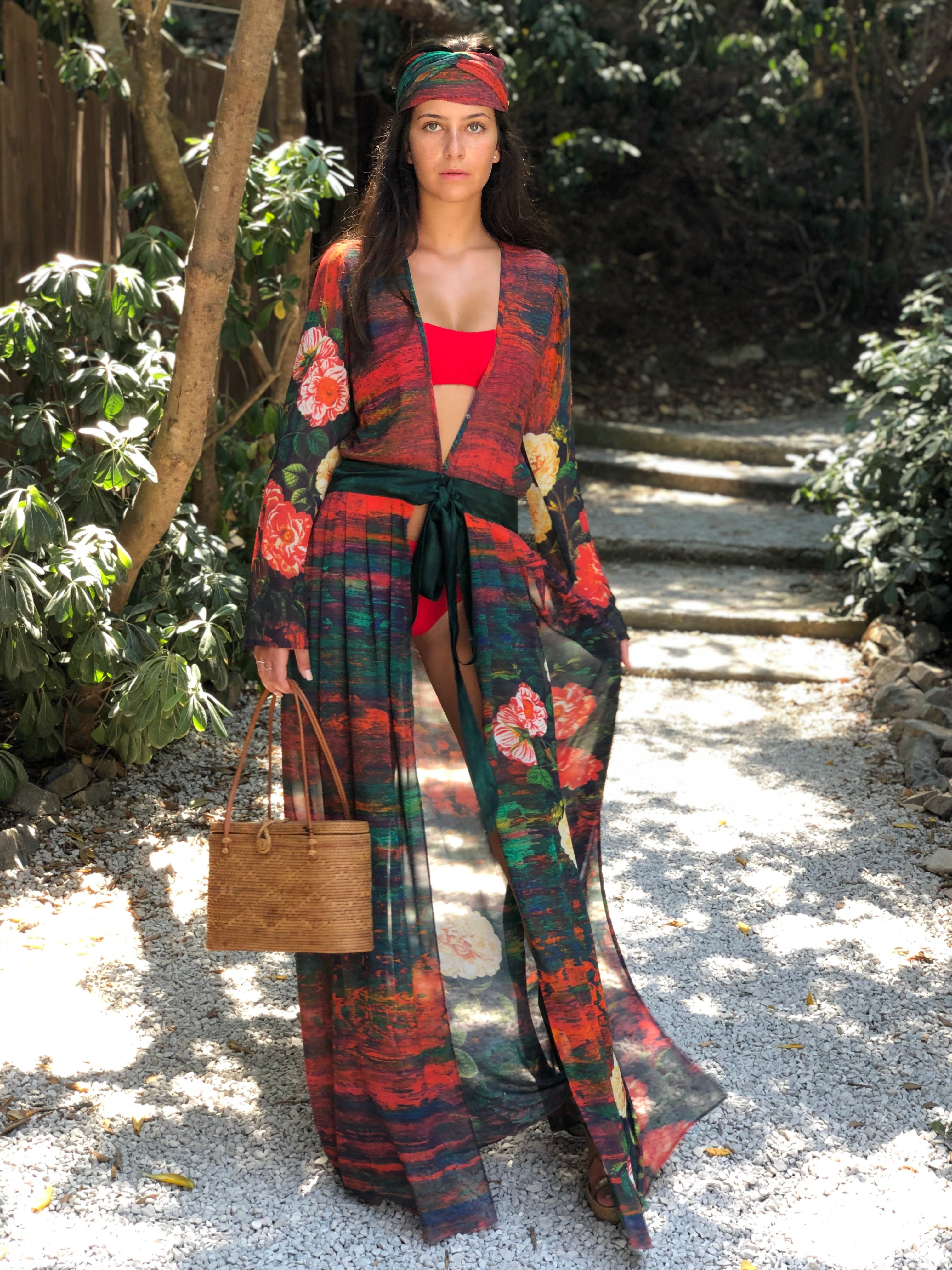 Woman in a colorful silk kimono dress standing outdoors with greenery in the background