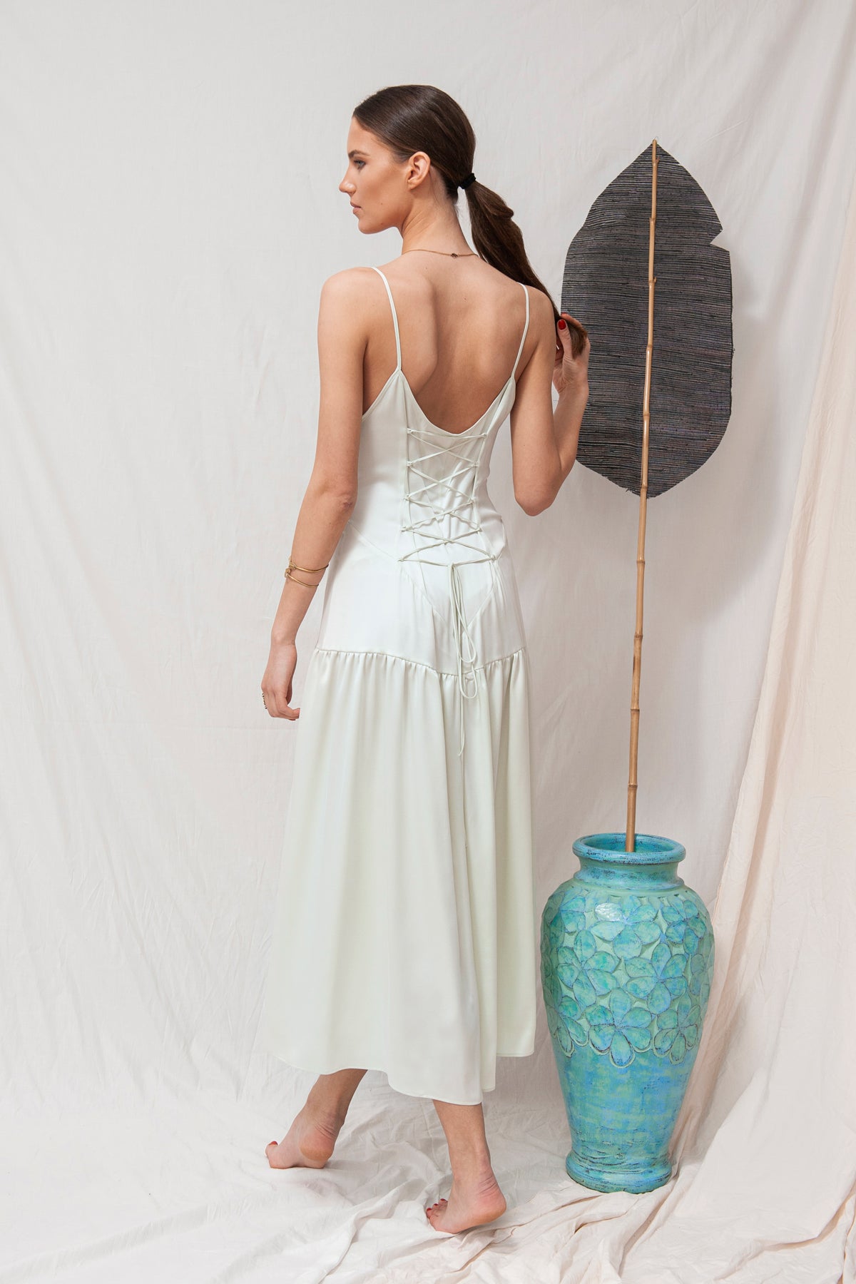 White sleeveless maxi dress with a low back and tiered skirt, sustainable and handmade organic fabric.