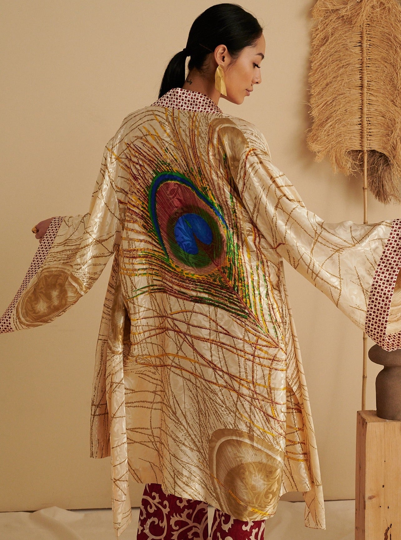 Sustainable handmade ruby red kimono with large peacock feather print and flowing sleeves, eco-friendly organic fabric.