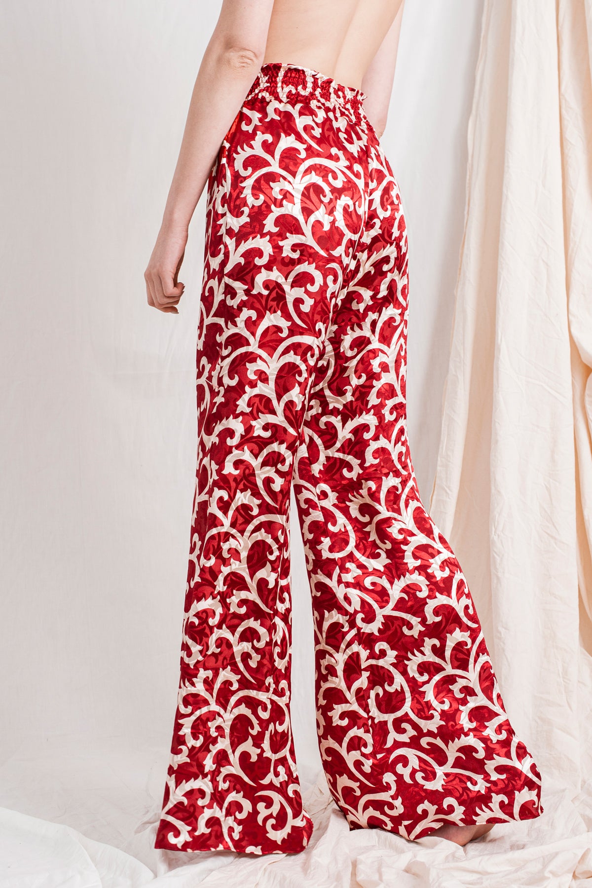 Red ruby flared trousers with white floral swirl pattern, sustainable and handmade organic fabric.